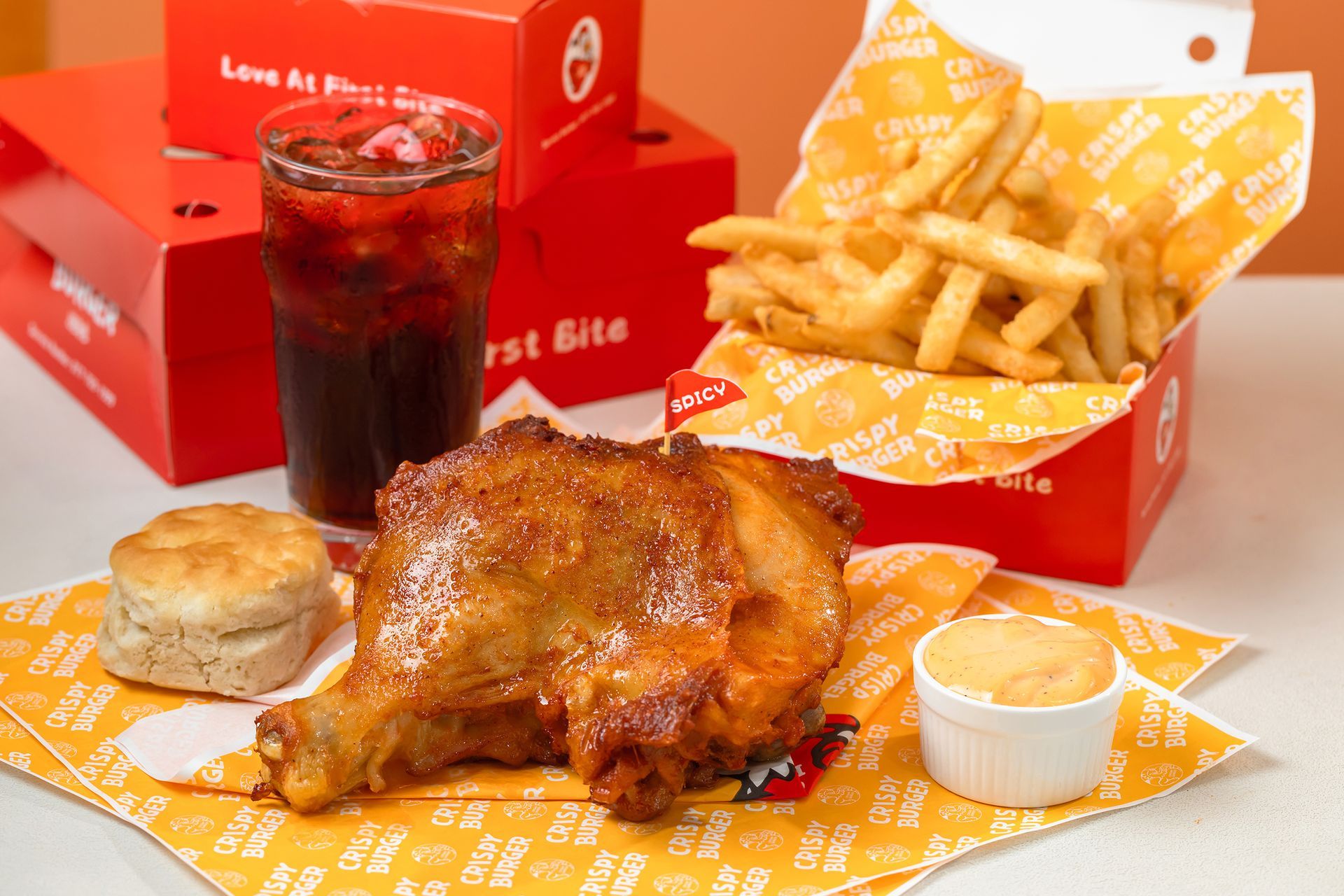 Roast chicken meal with fries, biscuit, dipping sauce, and a cola in red takeout boxes