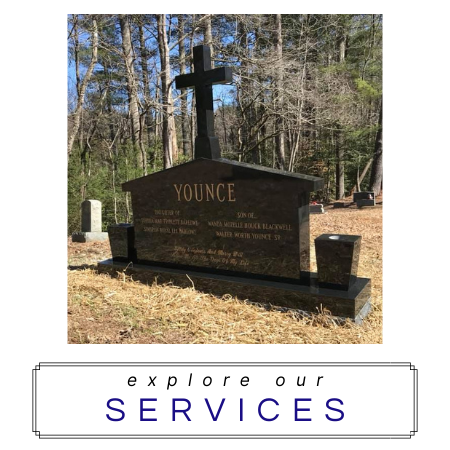 A black polished stone headstone with a cross on top in a cemetery, featuring the text 