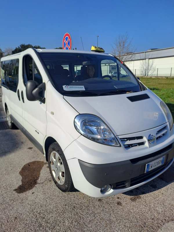Un taxi Nissan bianco parcheggiato sul ciglio della strada.