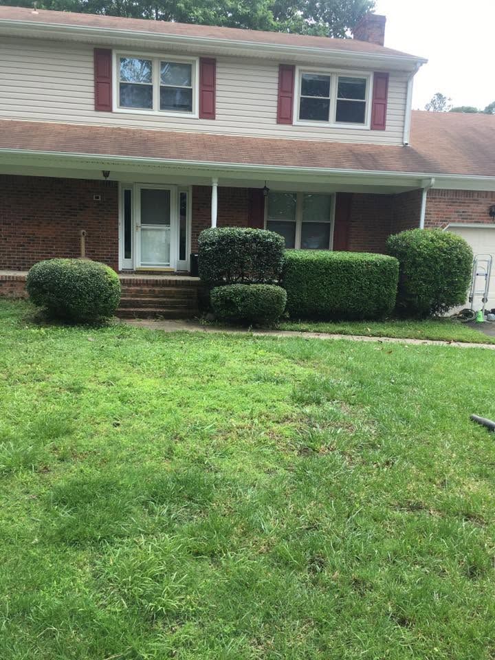 Two-story brick house with trimmed hedges and a green front lawn