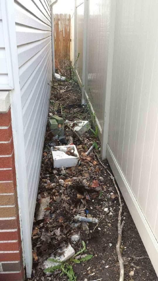 Narrow alley cluttered with trash and debris between two walls