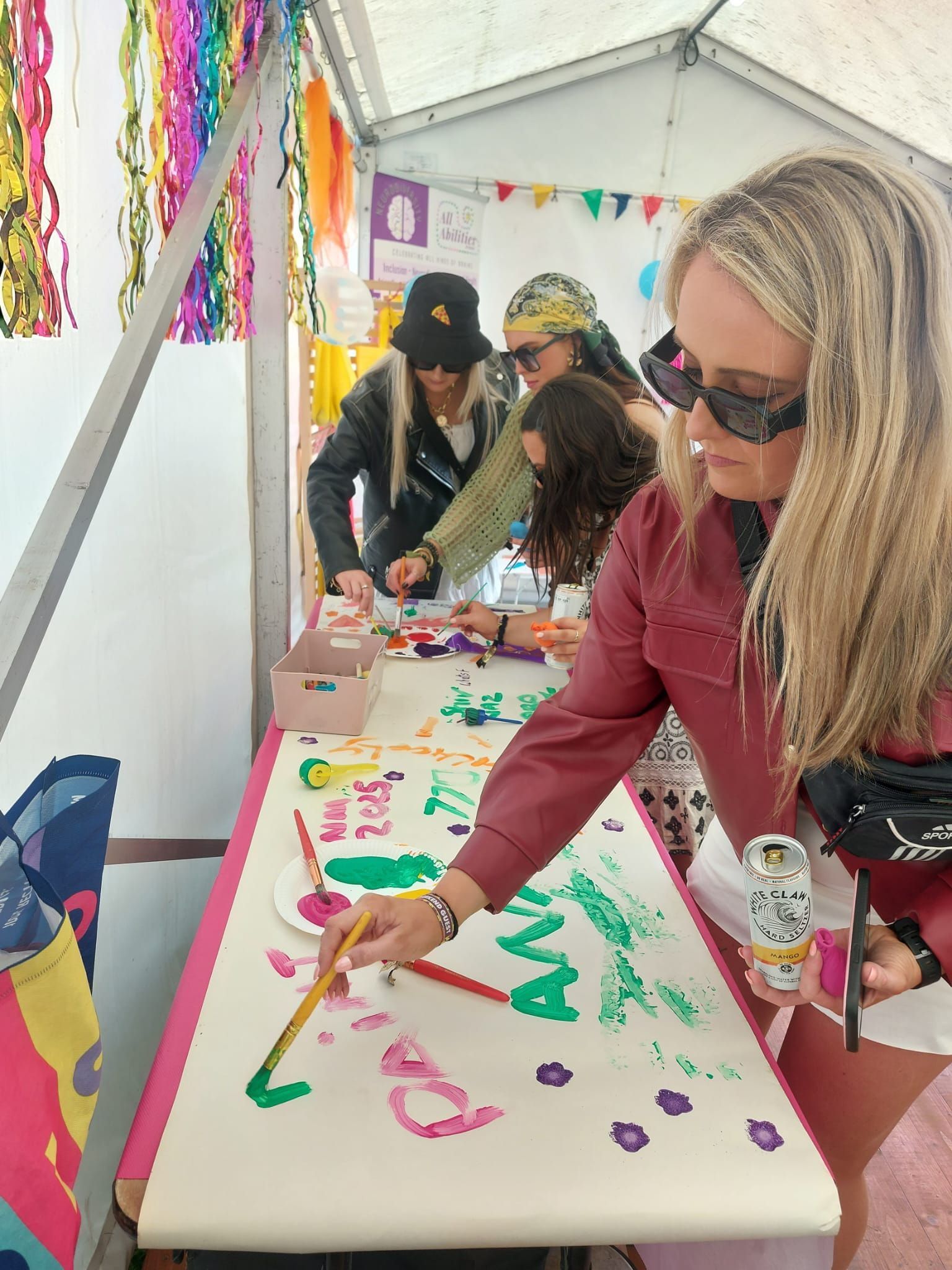 A woman at a festival writes with colored pencils on Whatman paper