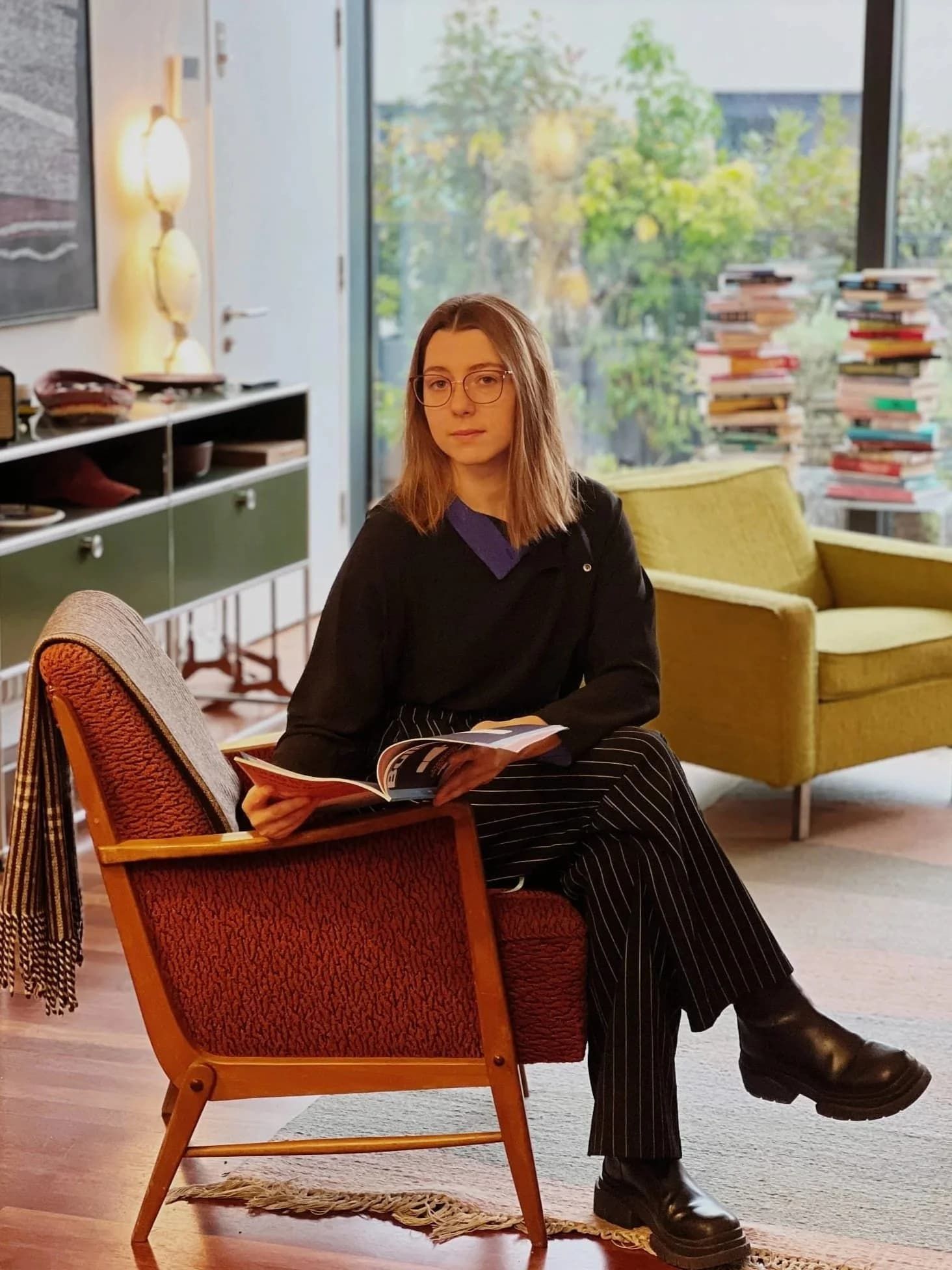 A young woman sitting in the chair and looking at the camera with an open book