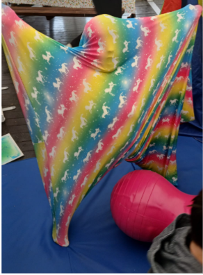 The kid is hiding in something like a big sock or colorful bag