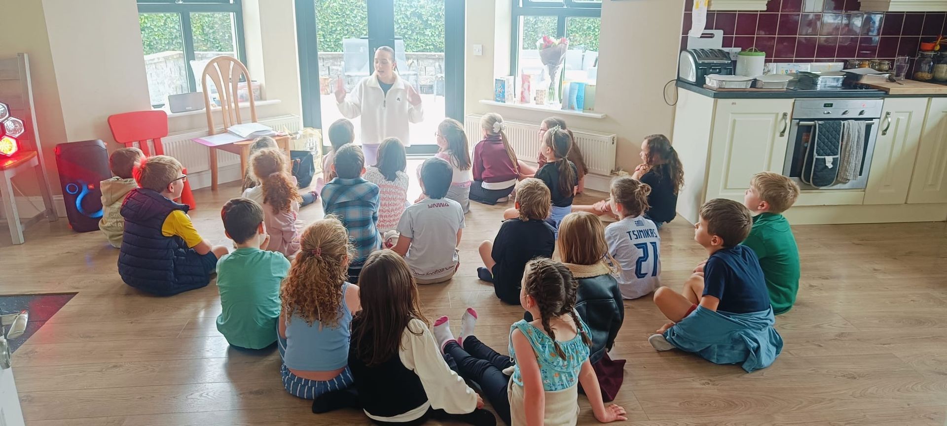 Children sit around the girl and listen to the story with enthusiasm.