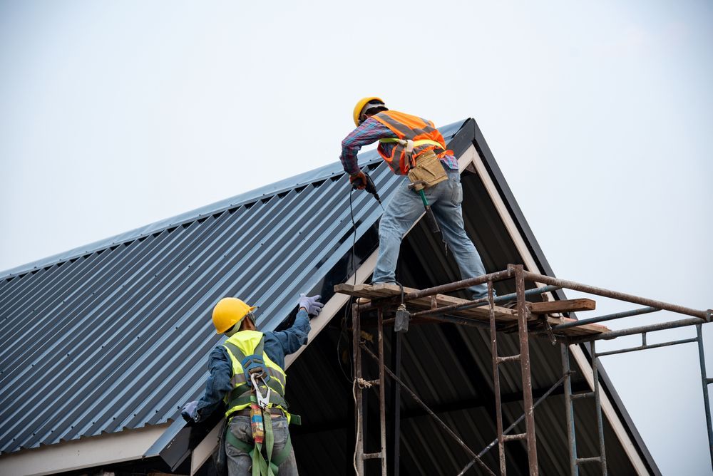 Two Roofers in Hard Hats and Safety Harnesses Install Metal Roofing — Vision Roofing Fascia & Gutter in Hervey Bay, QLD