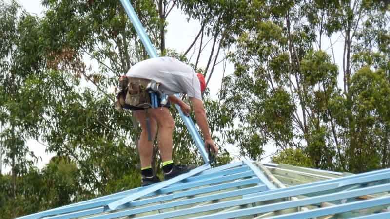 Construction Worker Installing Metal Roofing Structure Outdoors — Vision Roofing Fascia & Gutter in Hervey Bay, QLD