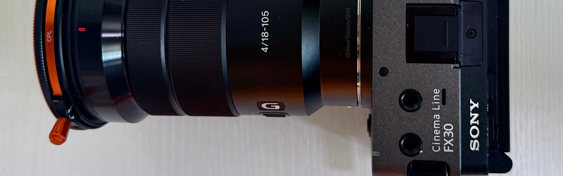 Close-up of a Sony camera lens with a black body and orange accent ring