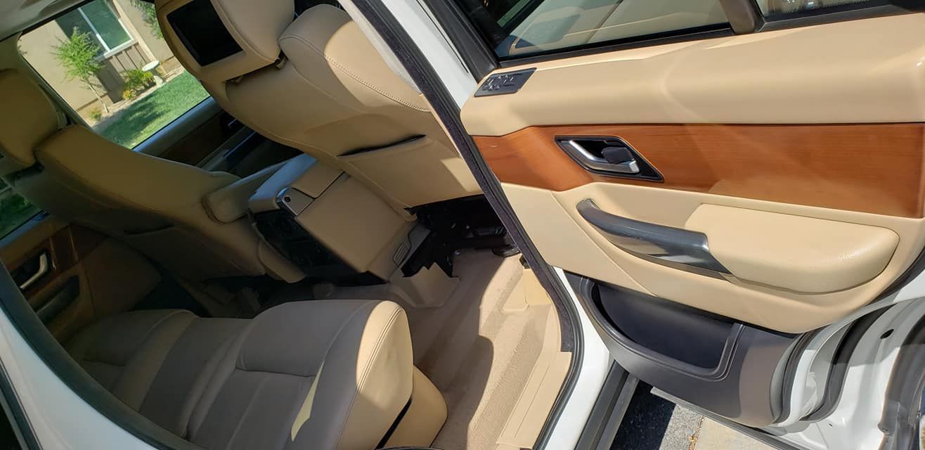 The inside of a white range rover with the door open.