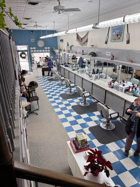 Hair salon interior with blue and white checkered floor, mirrors, chairs, and stylists.
