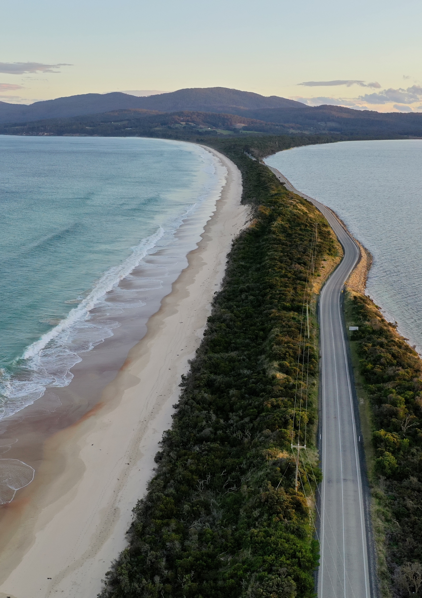 Coastal road with ocean on both sides, and lush green vegetation. Tasmanian Landscape