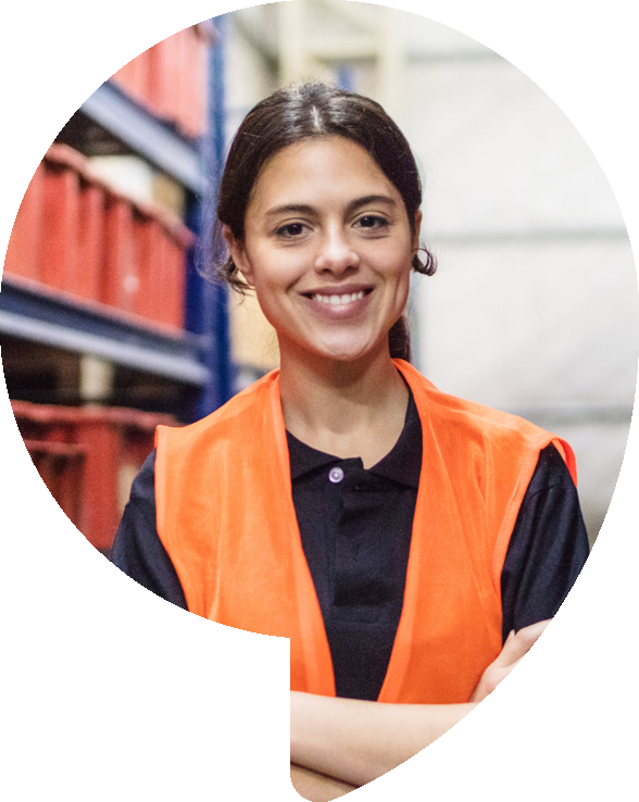 Smiling person wearing an orange safety vest, in a warehouse setting.