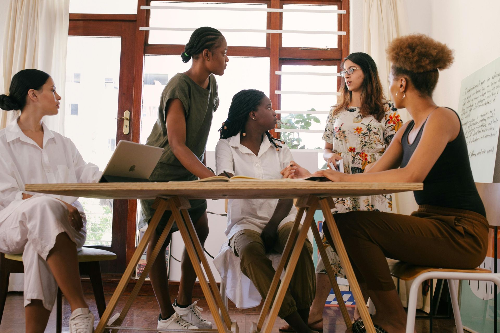 Women in a meeting around a table, discussing and collaborating, in an office space.