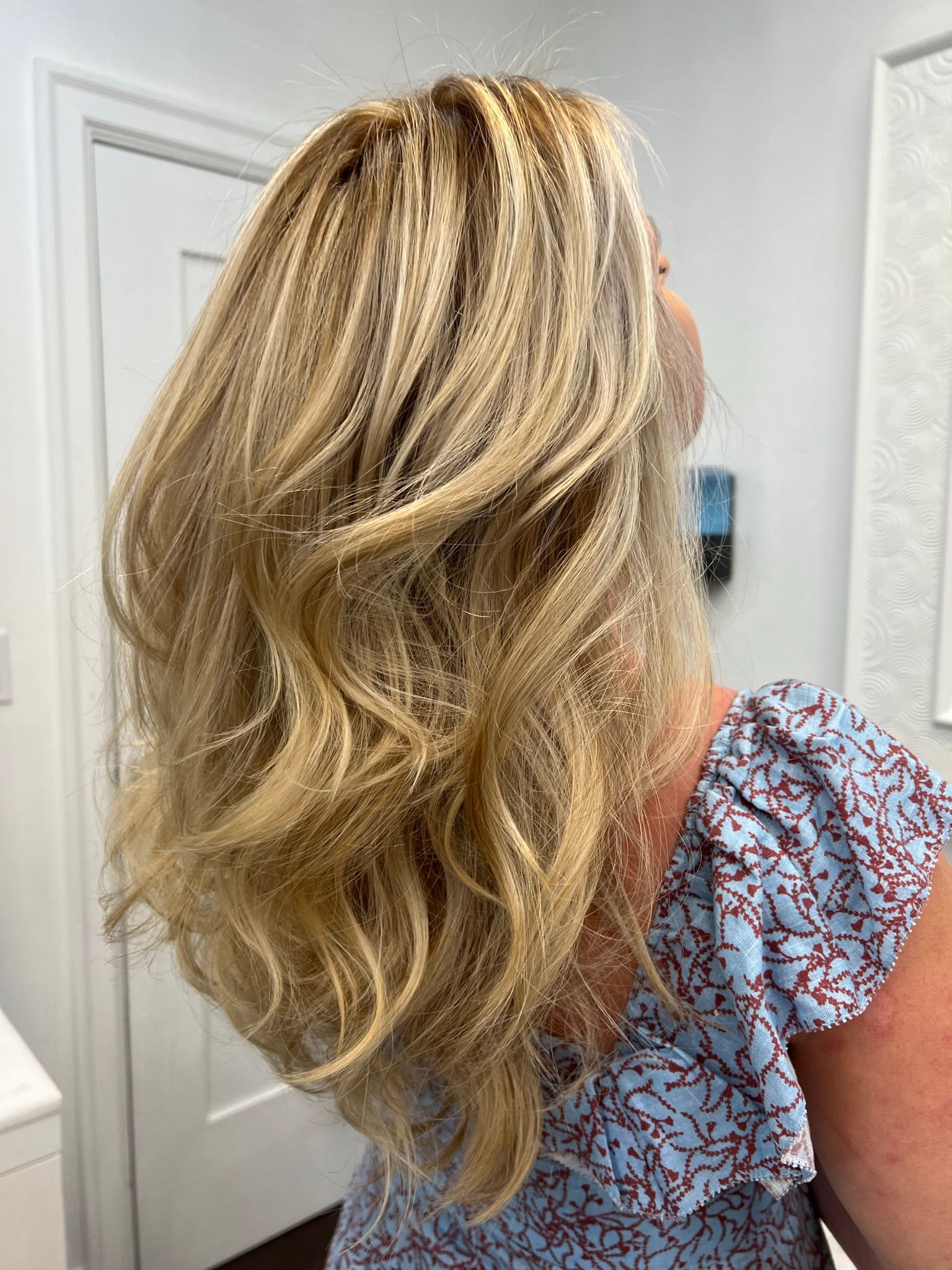 A woman with long blonde hair is wearing a blue floral shirt.