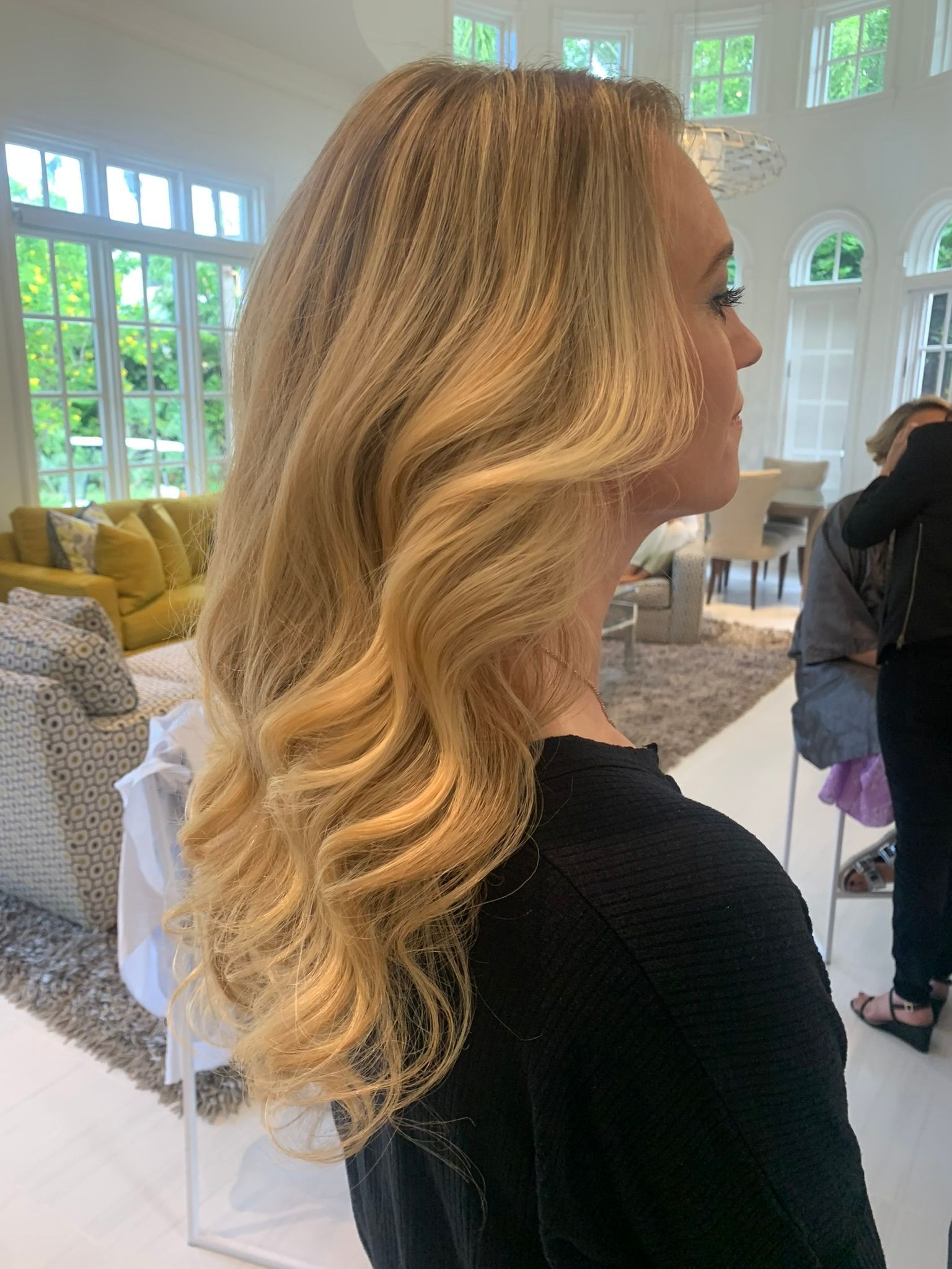 A woman with long blonde hair is standing in a living room.