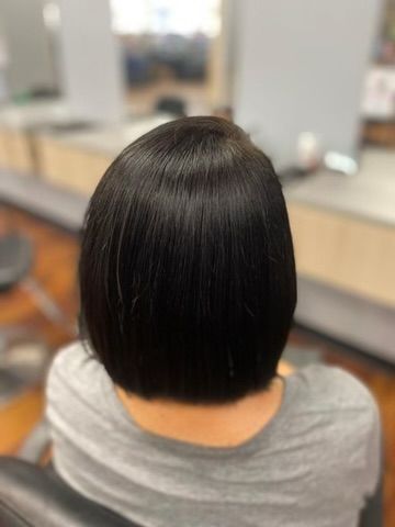 A woman with short black hair is sitting in a chair in a salon.