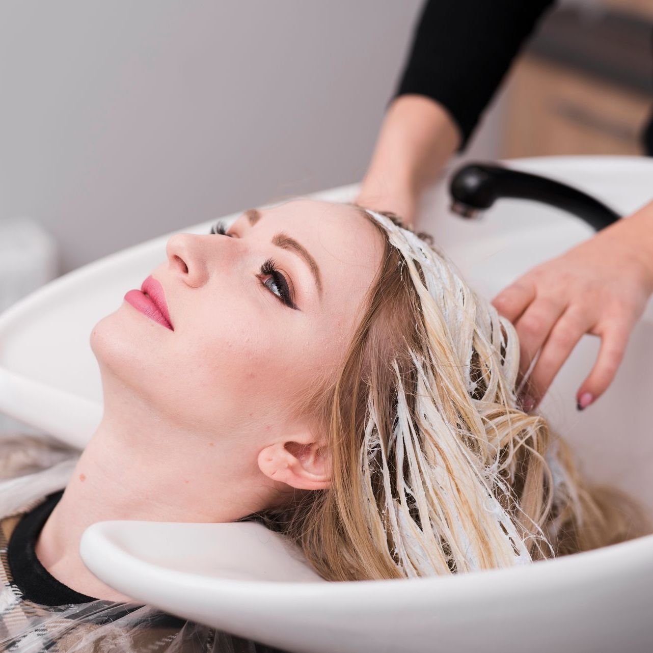A woman is getting her hair washed in a sink at a salon.