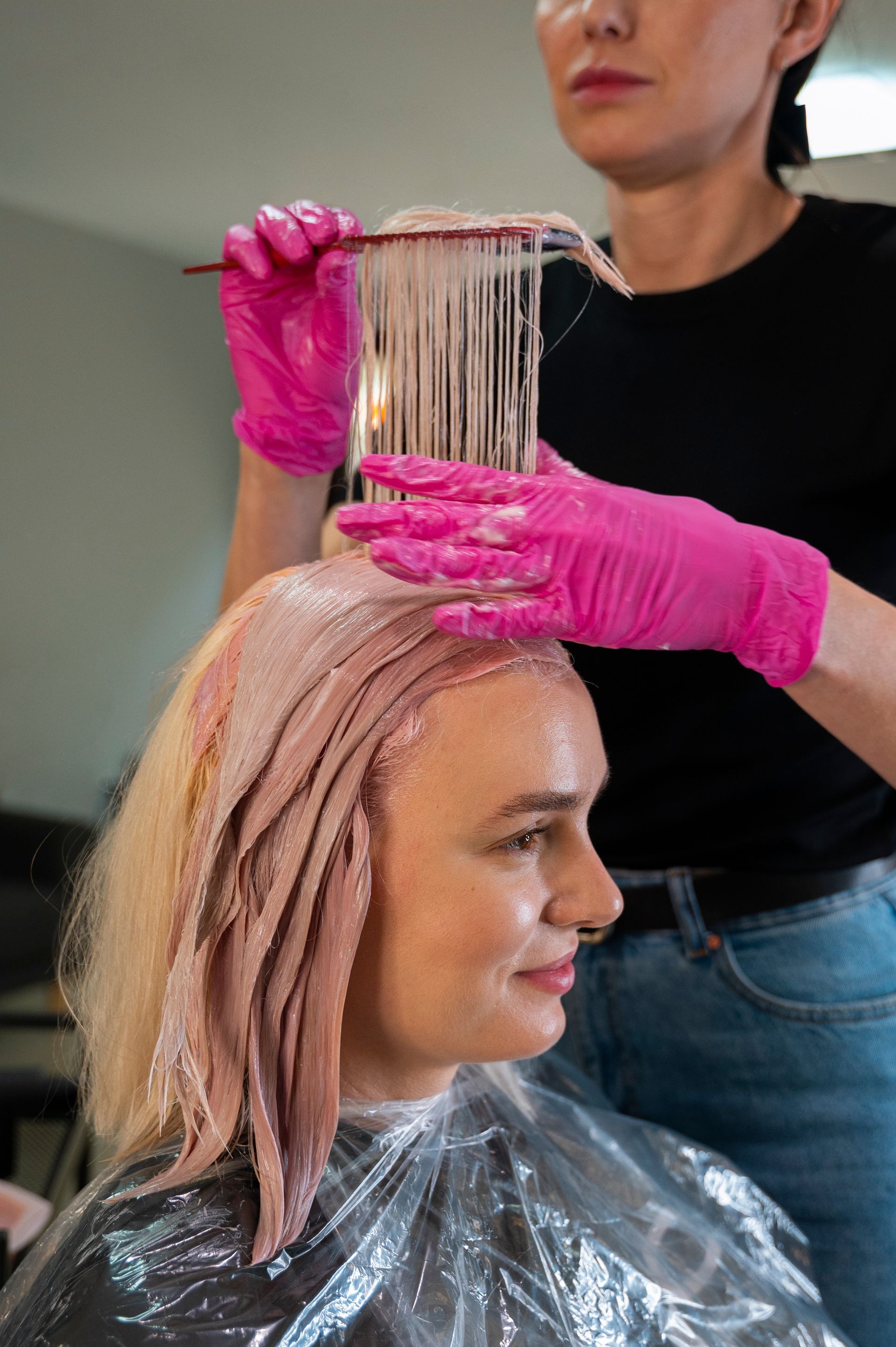 A woman is getting her hair dyed by a hairdresser in a salon.