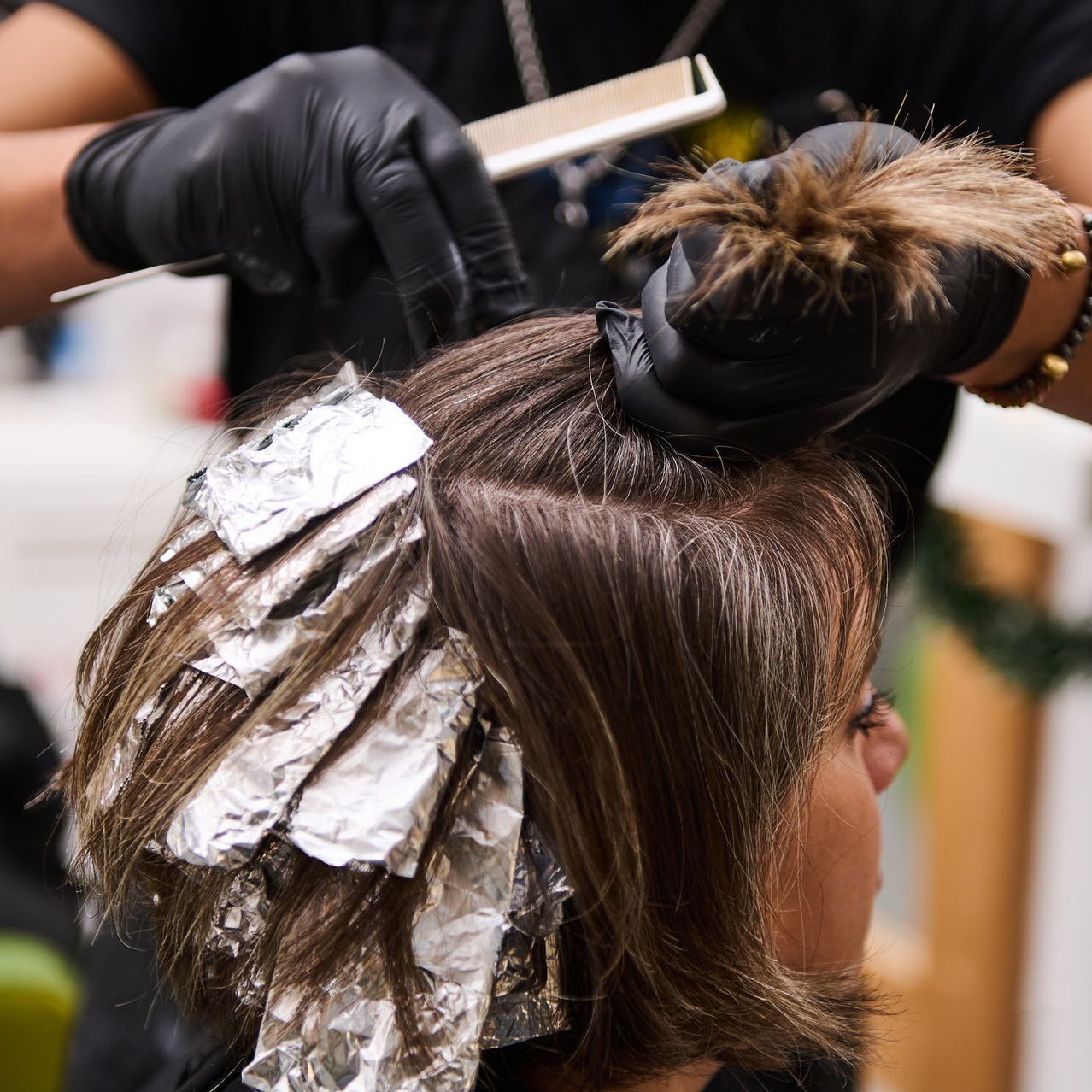 A woman is getting her hair dyed by a hairdresser