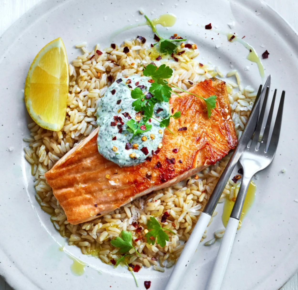 A white plate topped with rice and a piece of salmon