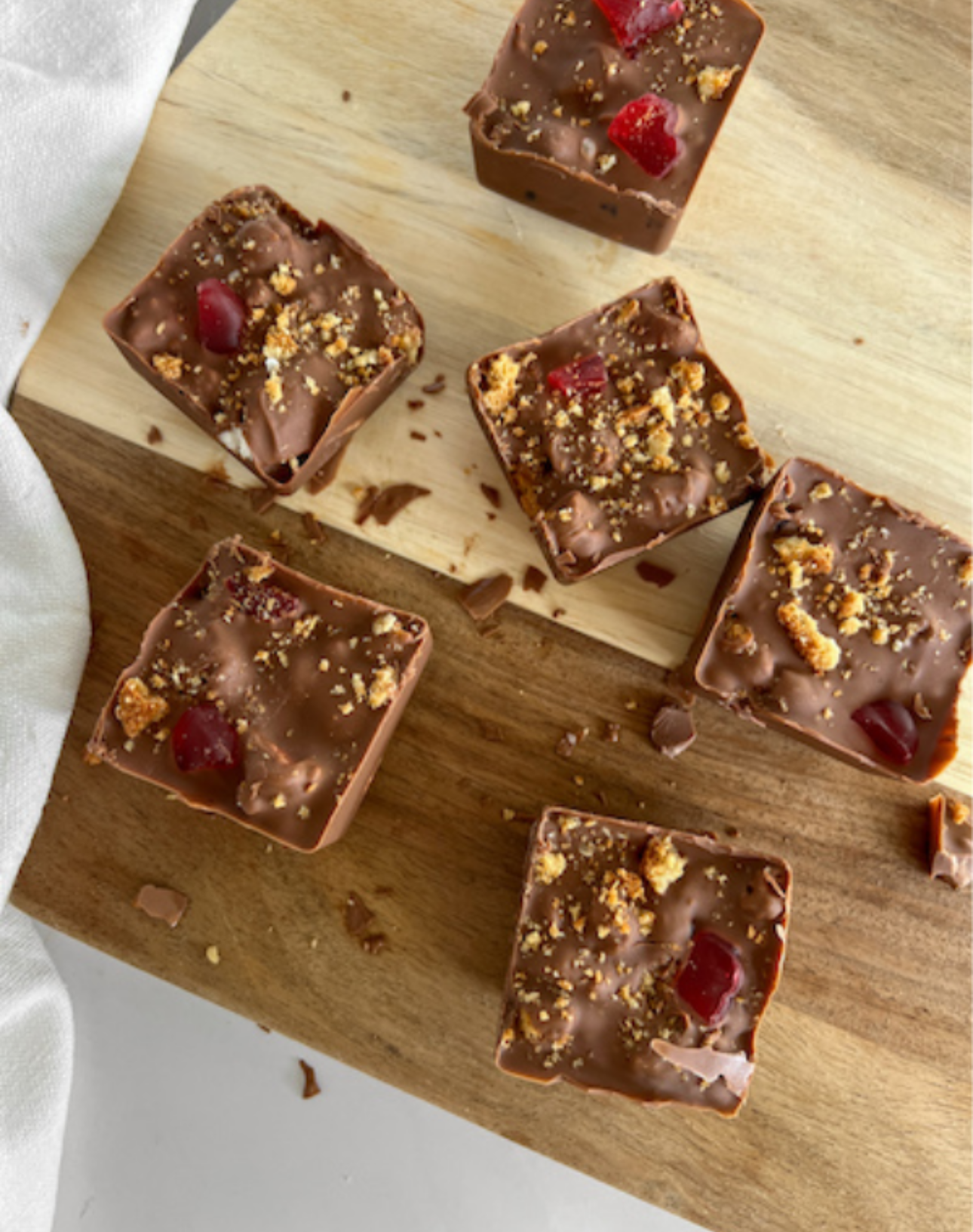 A wooden cutting board topped with chocolate squares and nuts