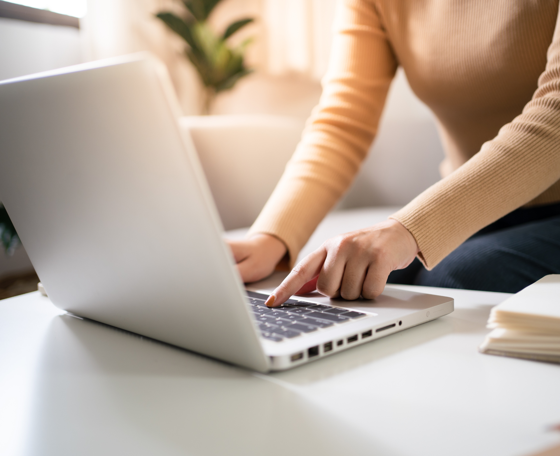 A woman is typing on a laptop computer while sitting on a couch.