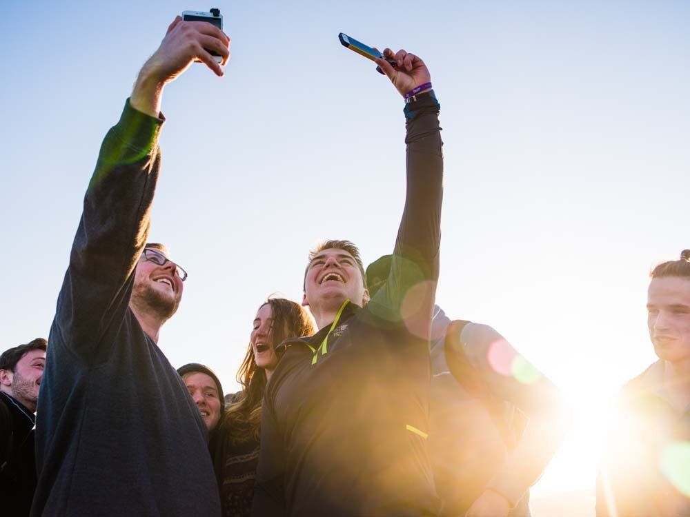 A group of people are taking a selfie with their cell phones.