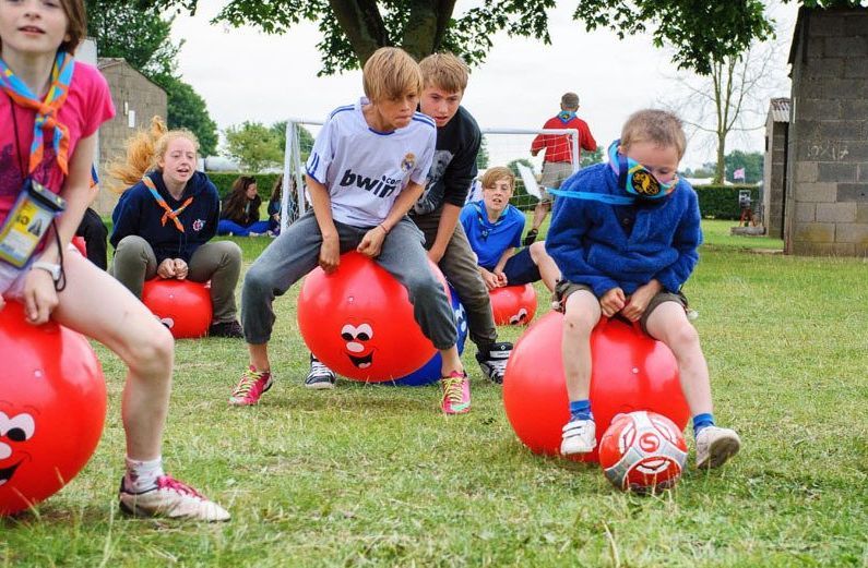 Young people having fun bouncing on bouncy balls and kick football.