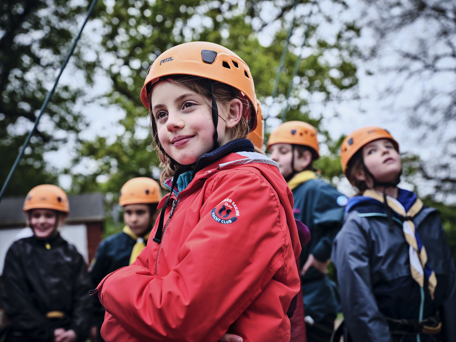 A group of children wearing helmets and jackets are standing next to each other.