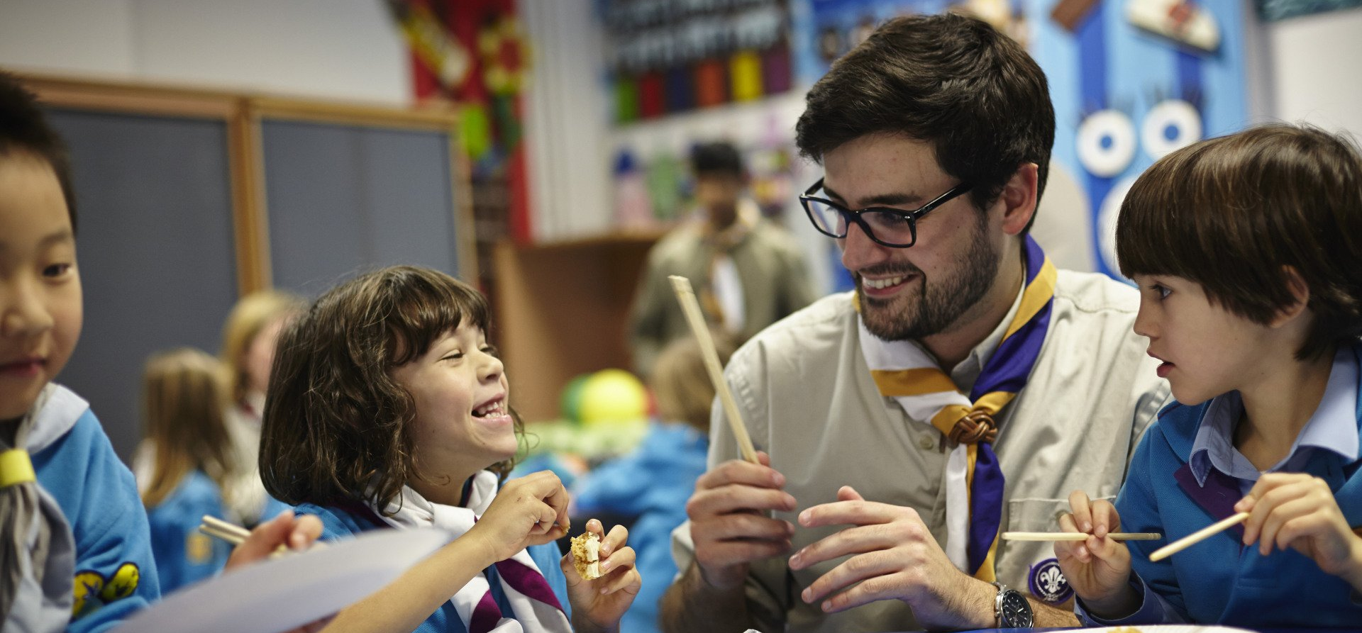 A man is teaching a group of children in a classroom.