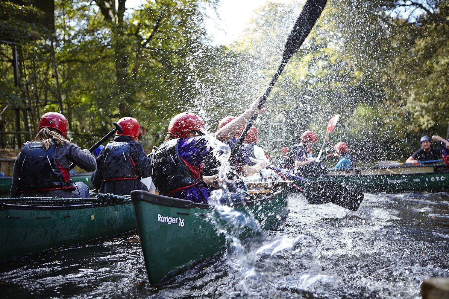 A group of people are rowing canoes down a river.