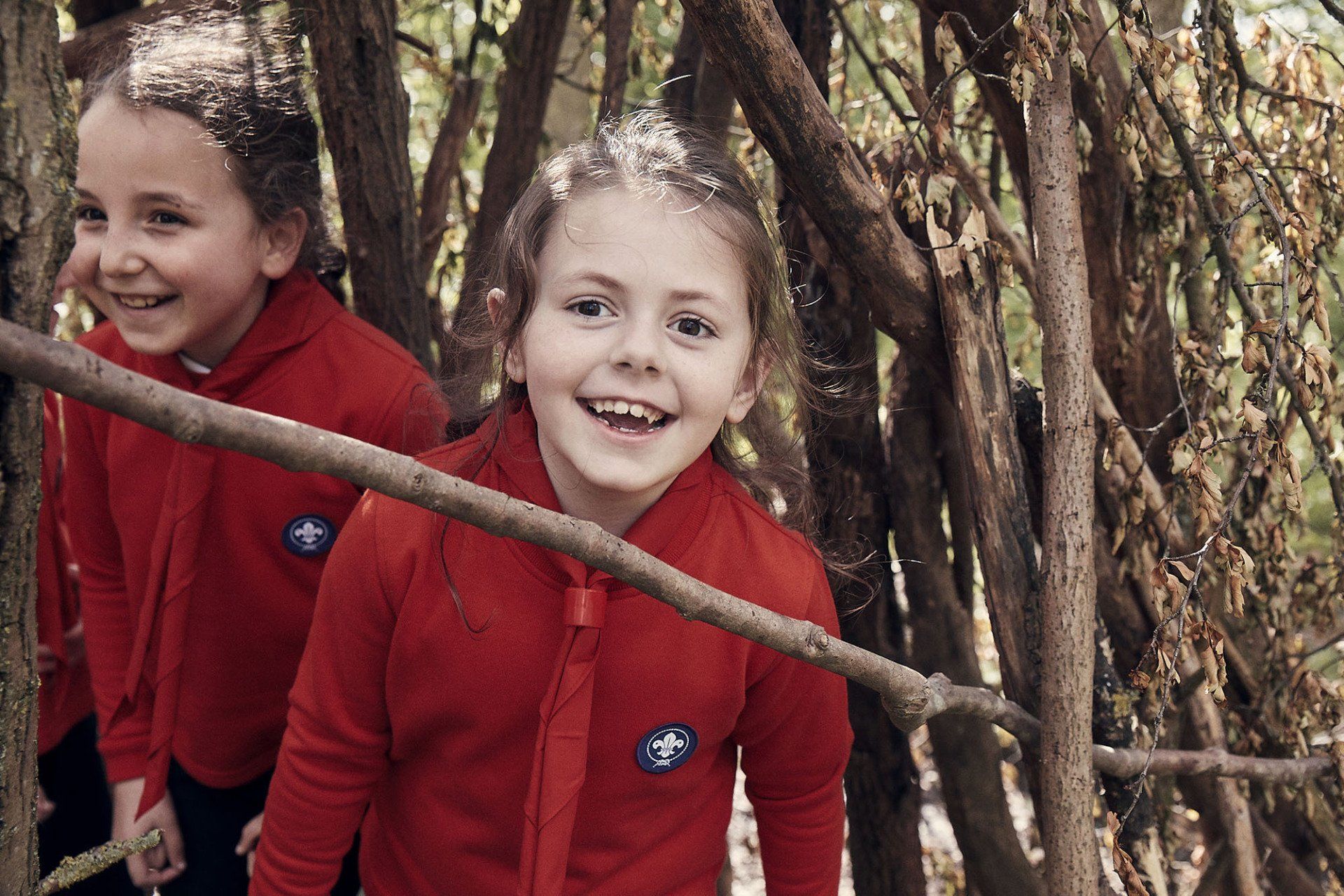 A group of young girls in red uniforms are playing in a tree house.