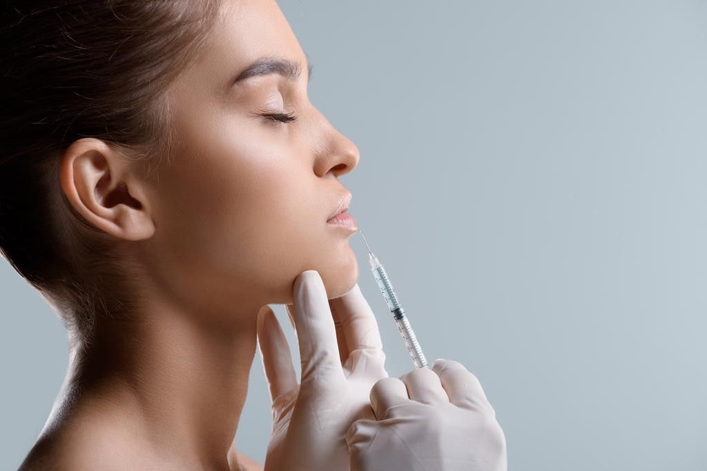 Uma mulher está recebendo uma injeção de botox no rosto.