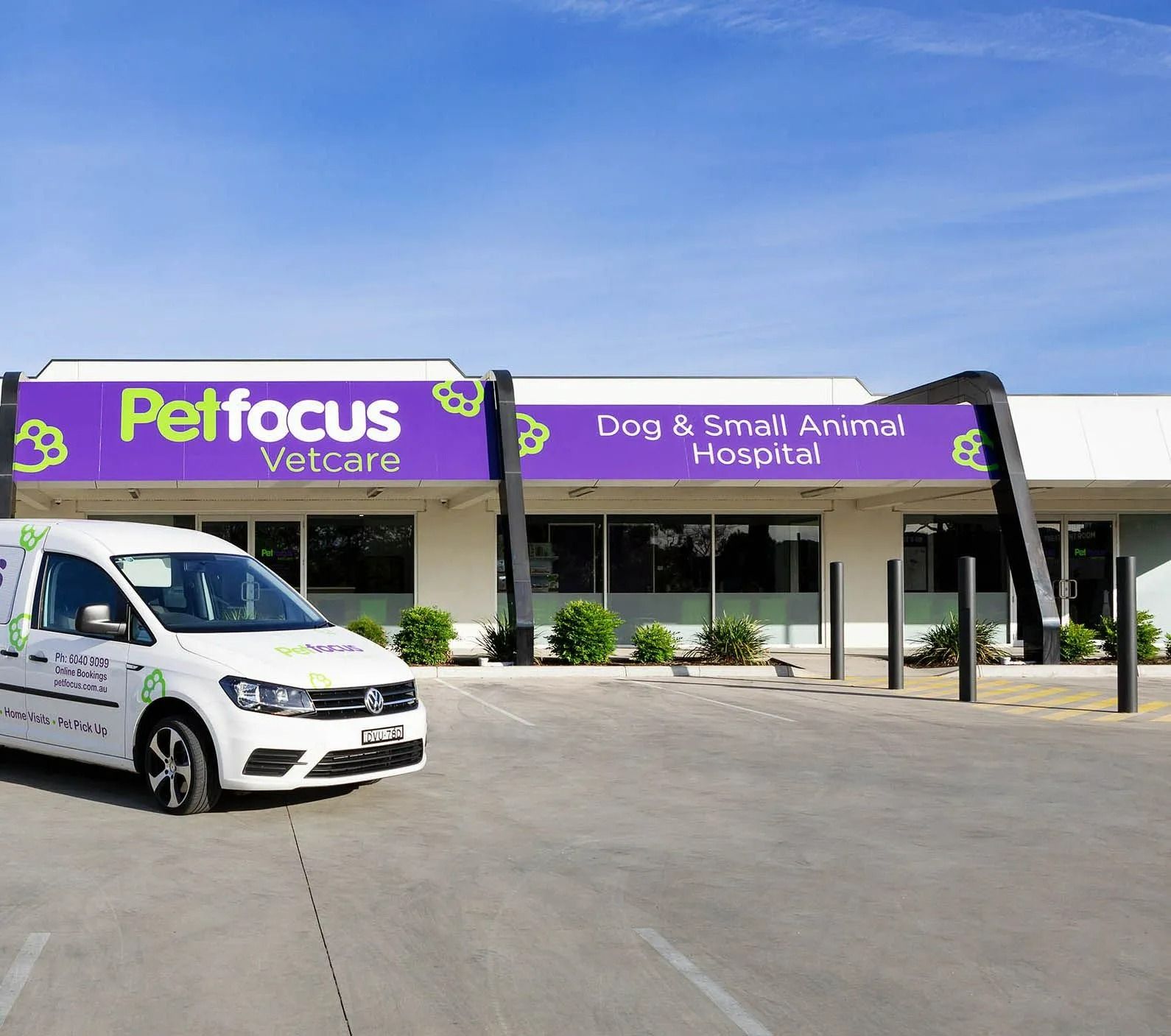 Petfocus Vetcare building with van in front. Purple signage, white building, blue sky.