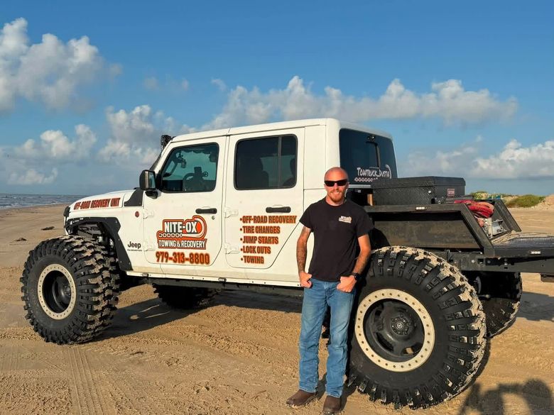 Dustin Janise, owner of Nite-Ox Towing, standing in front of his tow recovery truck.