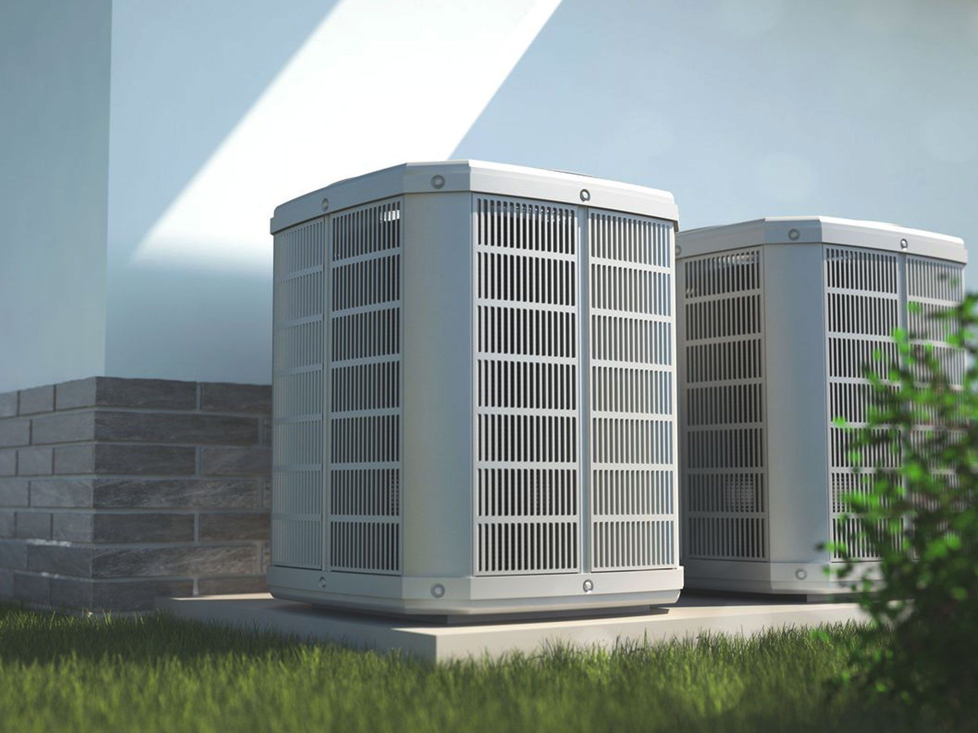 Two outdoor air conditioner units beside a house wall in sunlight