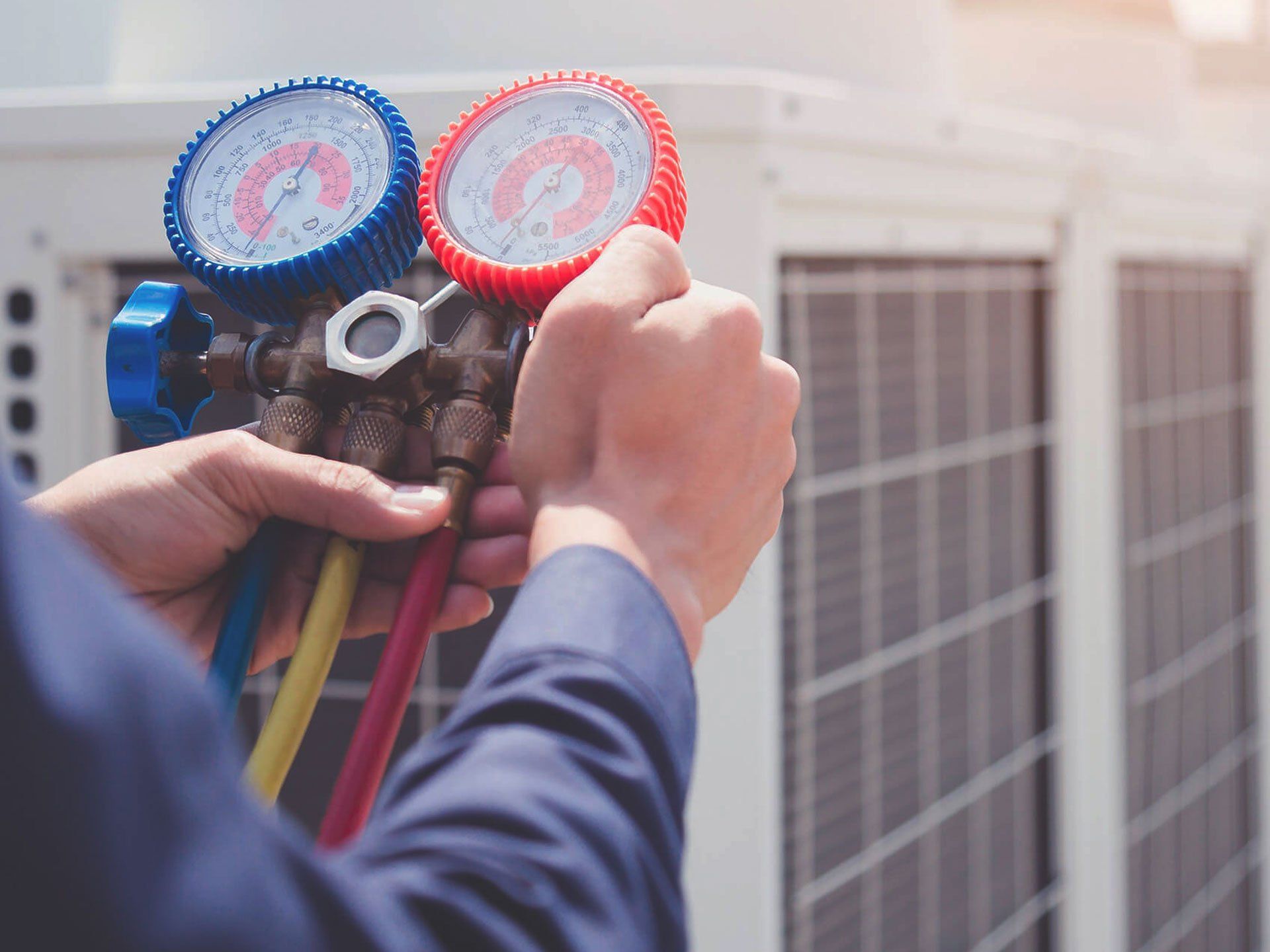 Technician adjusting gauges on an air conditioning unit outdoors