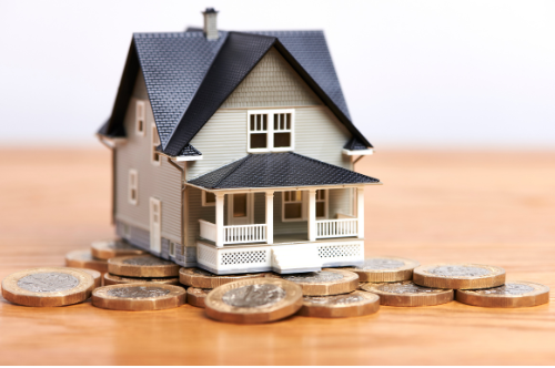 Miniature house model on stacked coins, symbolizing home savings or mortgage costs
