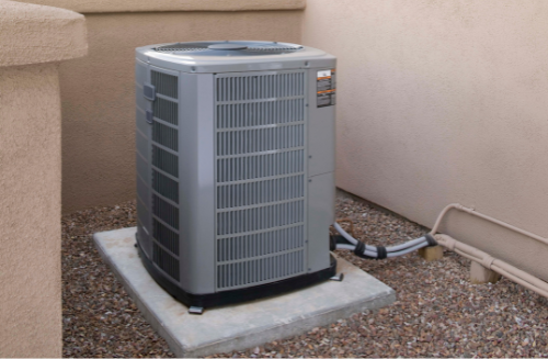 Outdoor air conditioning unit on a concrete pad beside a house wall.