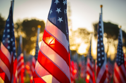 American flags waving outdoors at sunset, with one large flag in the foreground