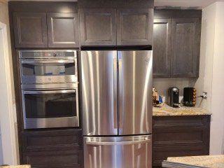 Modern kitchen with dark cabinets, stainless steel oven and refrigerator, and a granite countertop