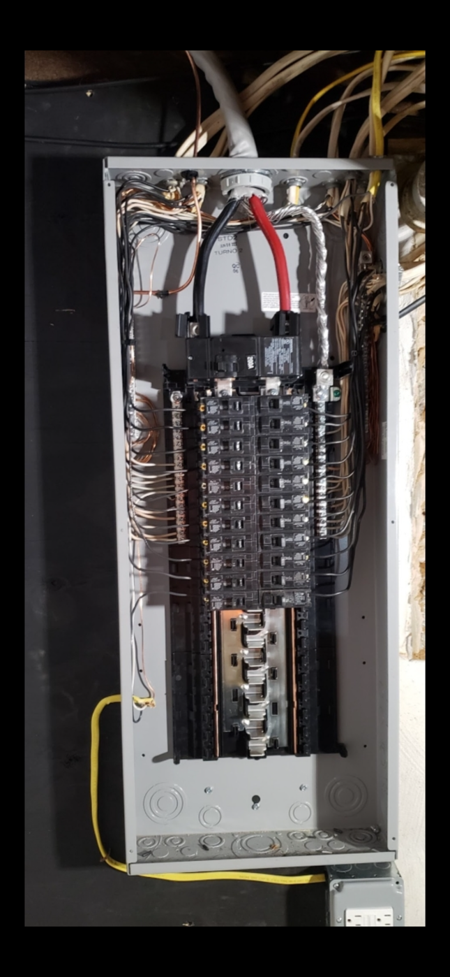 Open electrical breaker panel with rows of circuit breakers and visible wiring.
