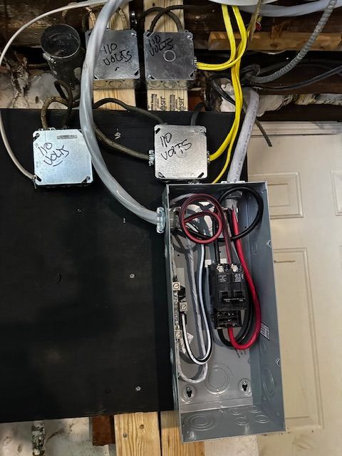 Open electrical panel with exposed wiring, breakers, and conduit mounted on a wall