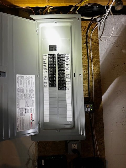 Open electrical breaker panel with circuit labels in a utility room.