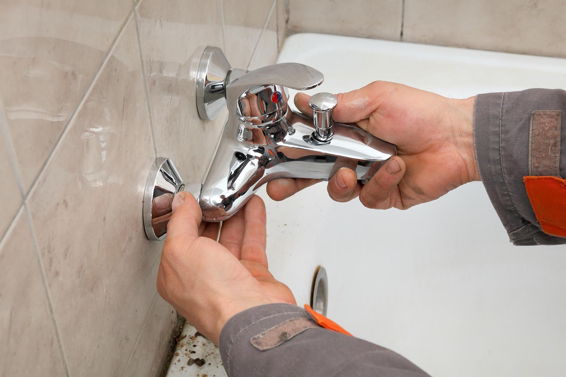 Plumbing replacement technician installing a new bathtub faucet in a residential bathroom. Plumbing replacement technician installing a new bathtub faucet in a residential bathroom.