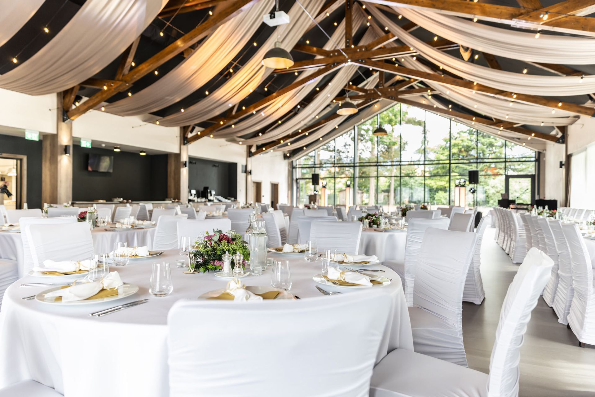 Elegant event hall with white draped ceiling and tables set for a banquet.