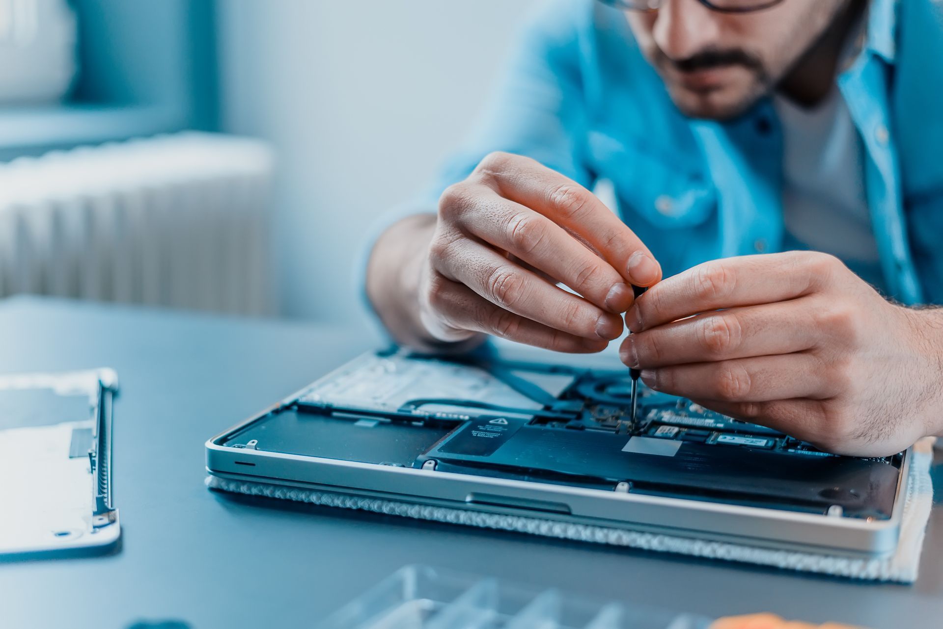 Close-up of a laptop being disassembled in a repair shop, showcasing an Apple MacBook repair.
