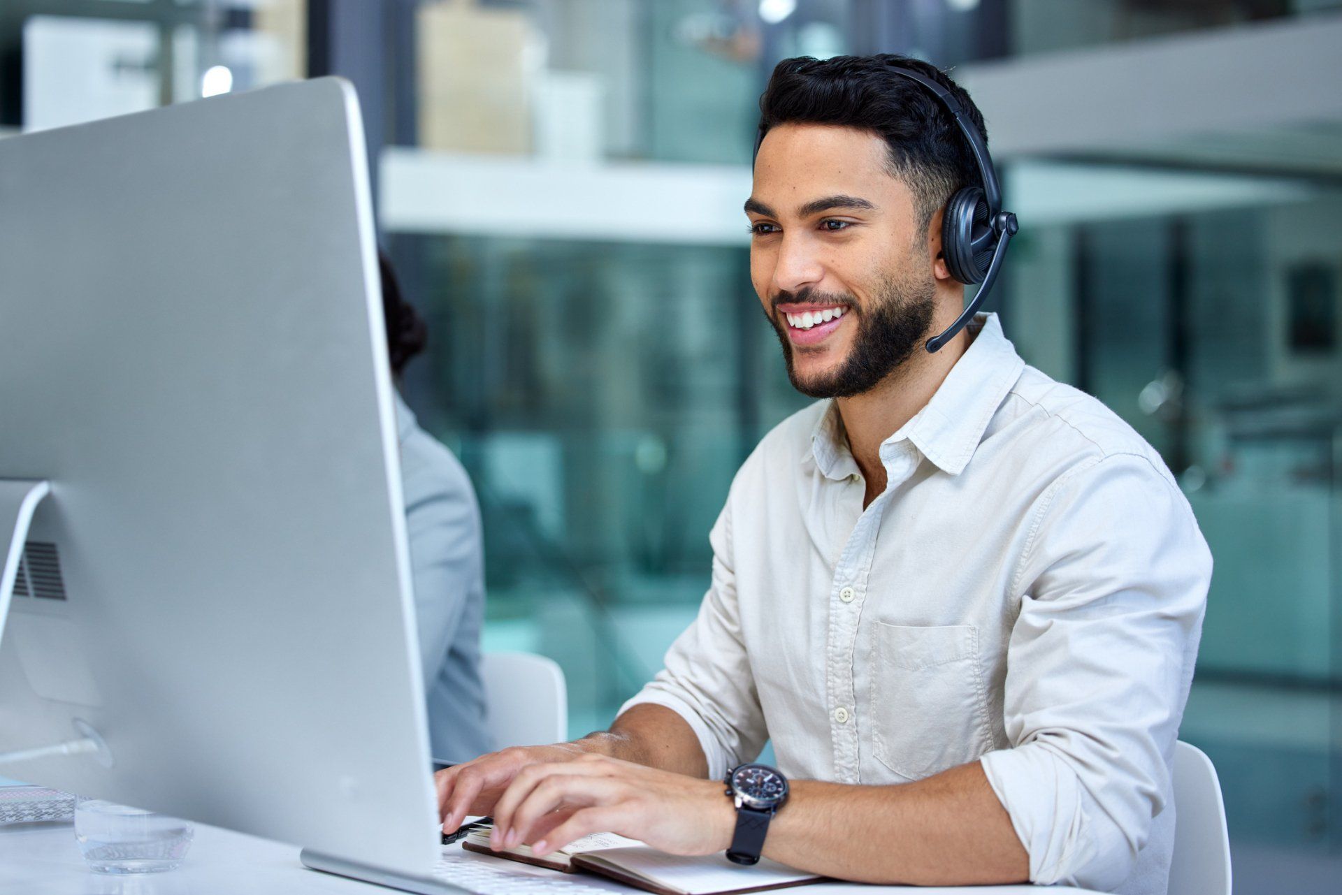A man wearing a headset is sitting in front of a computer.