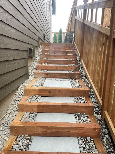 Wooden outdoor staircase with gray stone treads, next to a wood-planked wall.