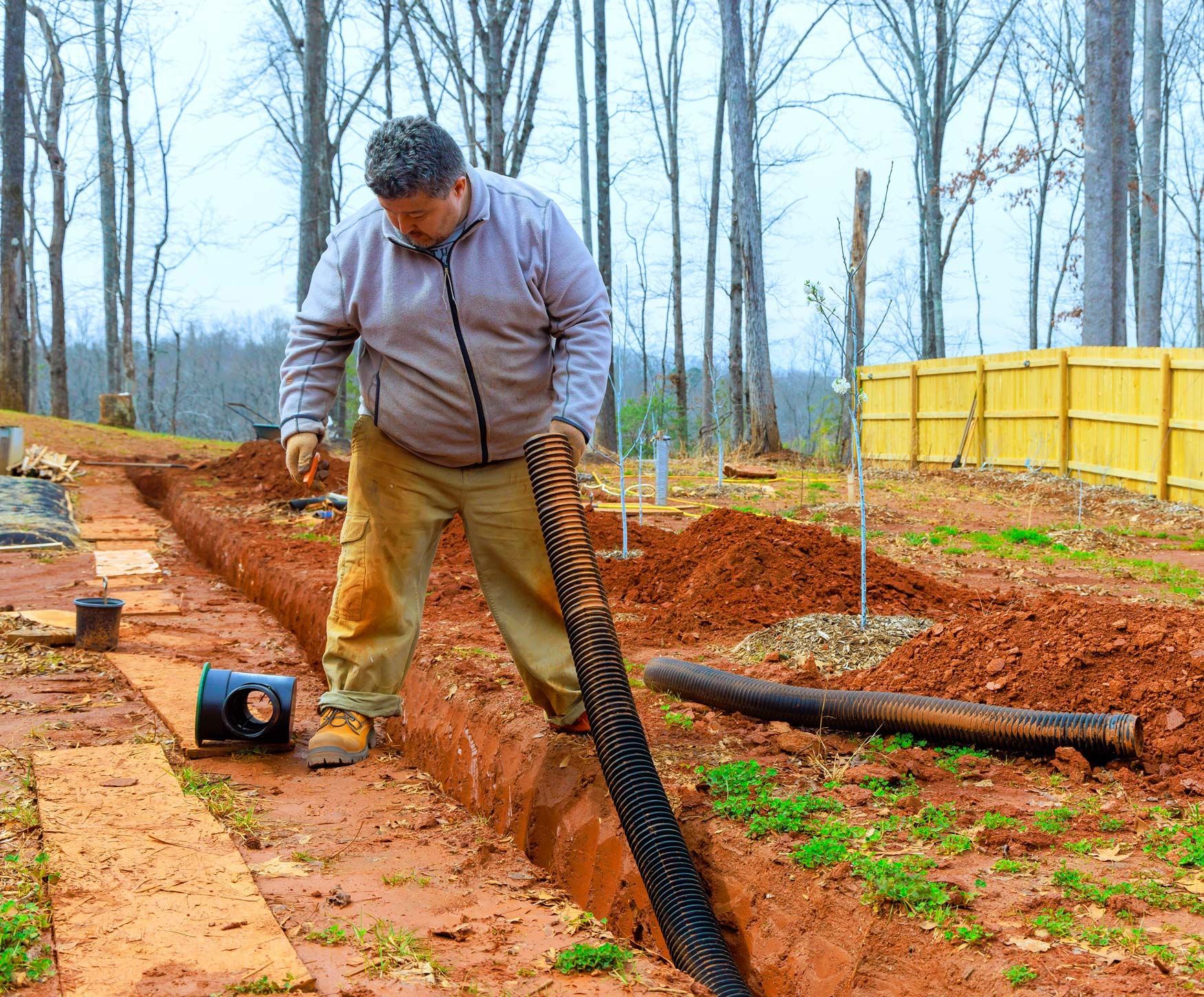 Worker works diligently to install drainage system in his backyard. Worker works diligently to install drainage system in his backyard.